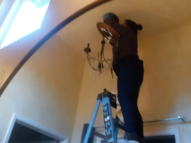 Electrician installing a chandelier in a Cherry Hill residence